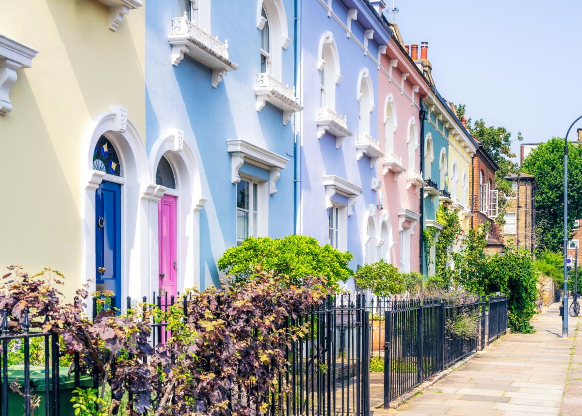 A clear blue summer sky above pastel coloured traditional townhouses in Hammersmith, West London.