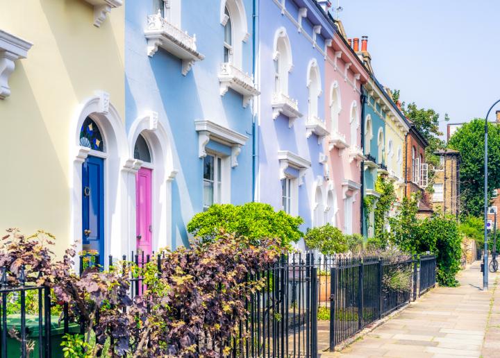 A clear blue summer sky above pastel coloured traditional townhouses in Hammersmith, West London.