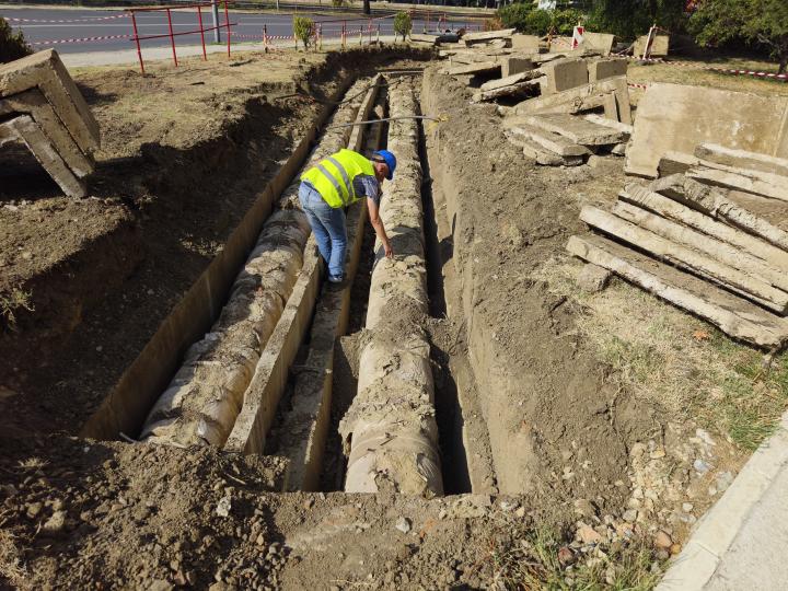 Man repairing old district heating pipeline in concrete trench