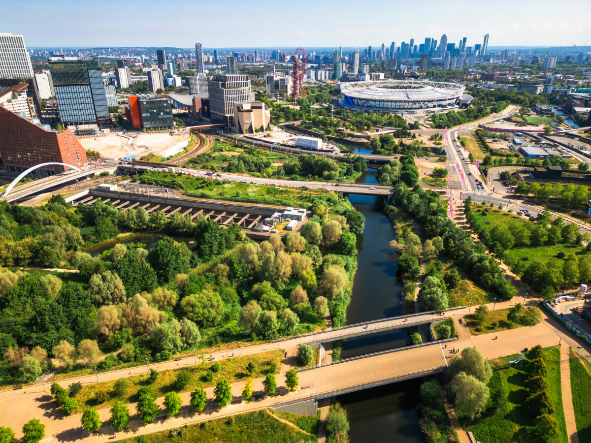 Aerial view, taken by drone, depicting the architecture of Stratford in East London. In the foreground is Stratford wetlands on the River Lea, while the skyline is dominated by Queen Elizabeth Olympic Park and the London Stadium,. On the horizon is the business district and skyscrapers - including Canary Wharf - of the Isle of Dogs.