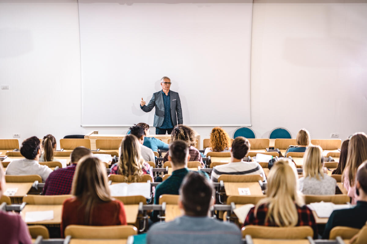 Professor giving a lecture in front of projection screen at lecture hall