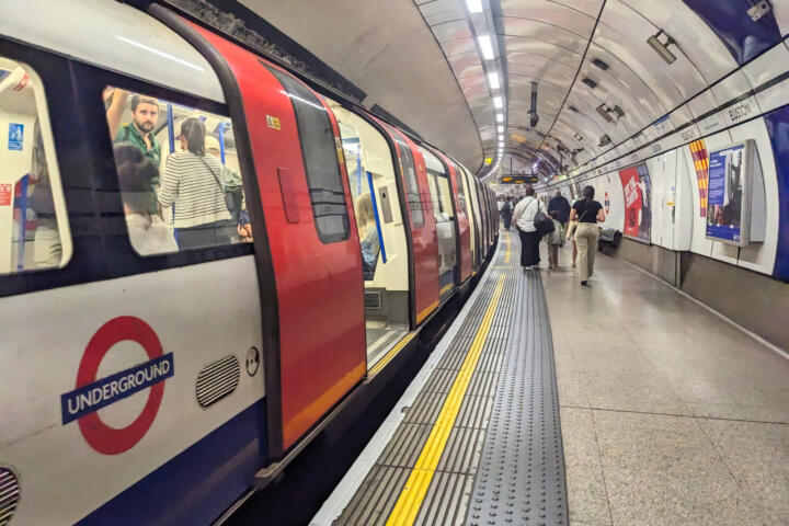 A classic red and white Northern Line London Underground train stopped with open doors at the curved platform of Euston station as passengers leaving the train
