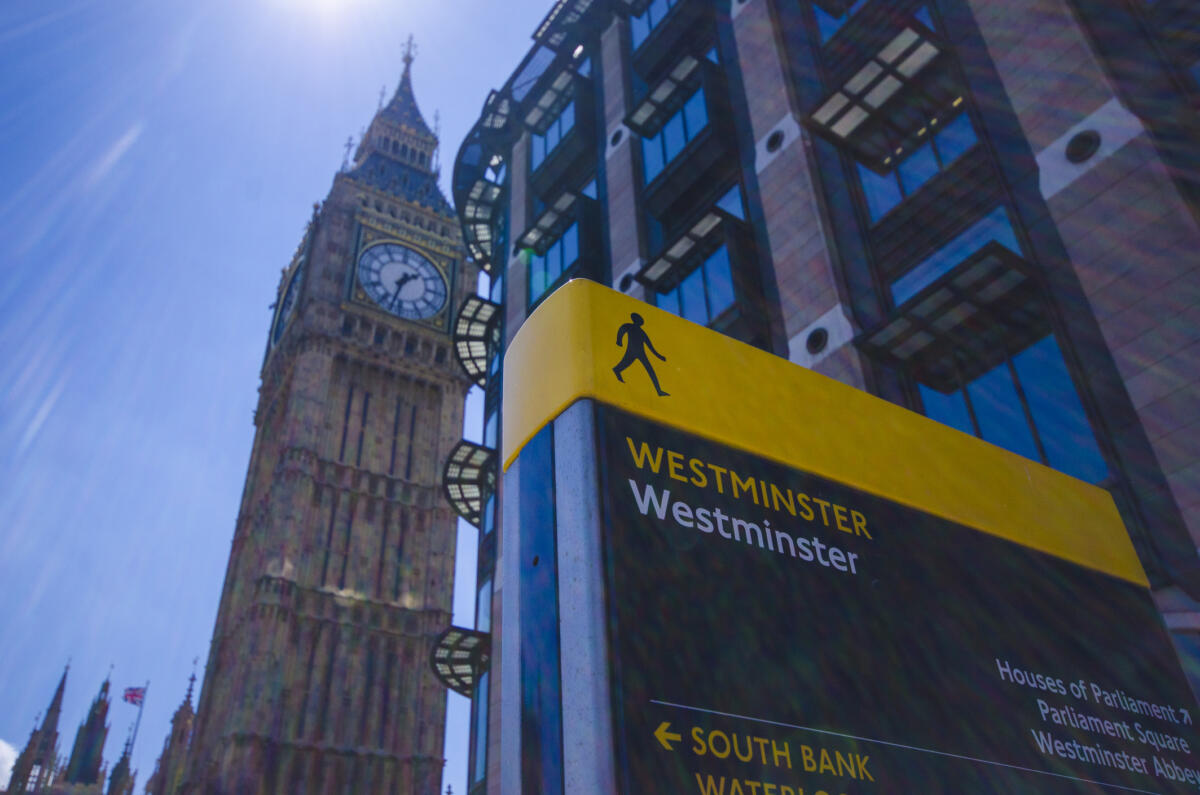 Big Ben on the left, with a sign for 'Westminster' on the right in front of some buildings